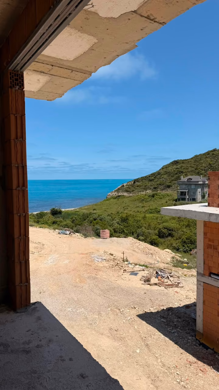 An unfinished opening toward a green coastal slope and the sea. Undated photograph supplied in the construction source folder; it does not establish the current completion status.