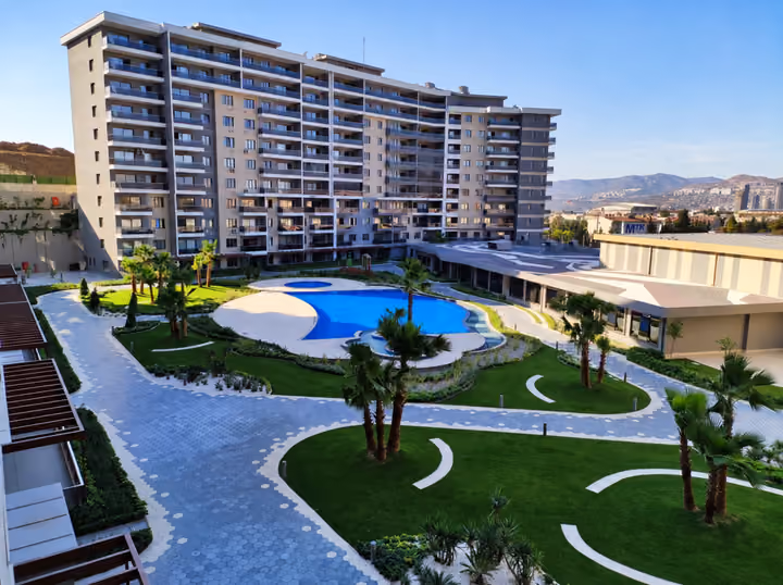 Photograph of the apartment blocks, outdoor pool basin and landscaped pedestrian paths.