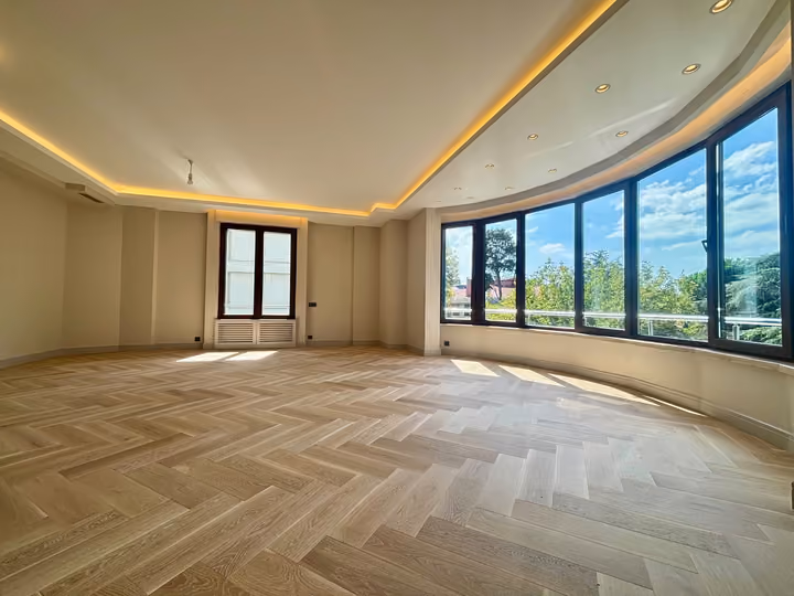 Living room with a curved window wall overlooking trees.