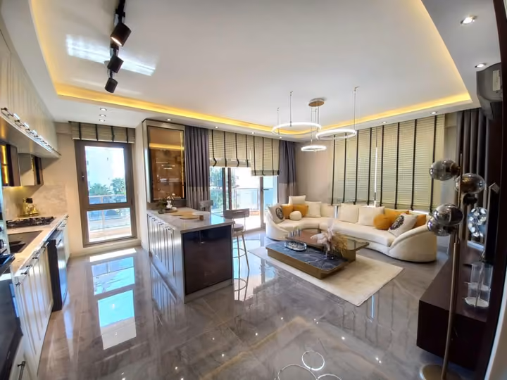 A furnished show apartment open living area with a kitchen island and balcony doors.