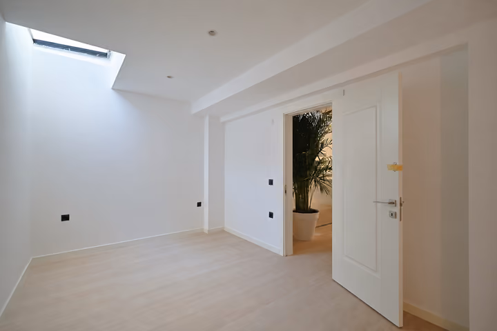 Unfurnished room with a skylight and an open door to the hallway.