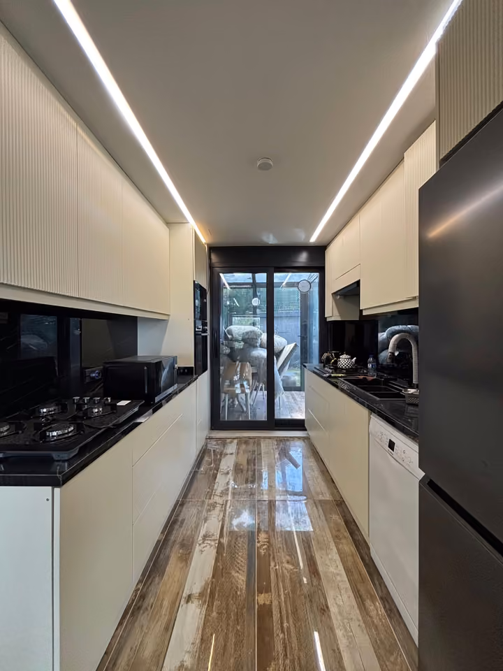 Separate galley kitchen with cabinets and appliances.