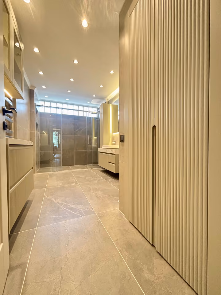Bathroom entrance with storage cabinetry and a glass shower enclosure.