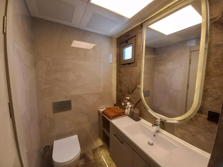 A show apartment bathroom vanity and wall mirror beside the toilet.
