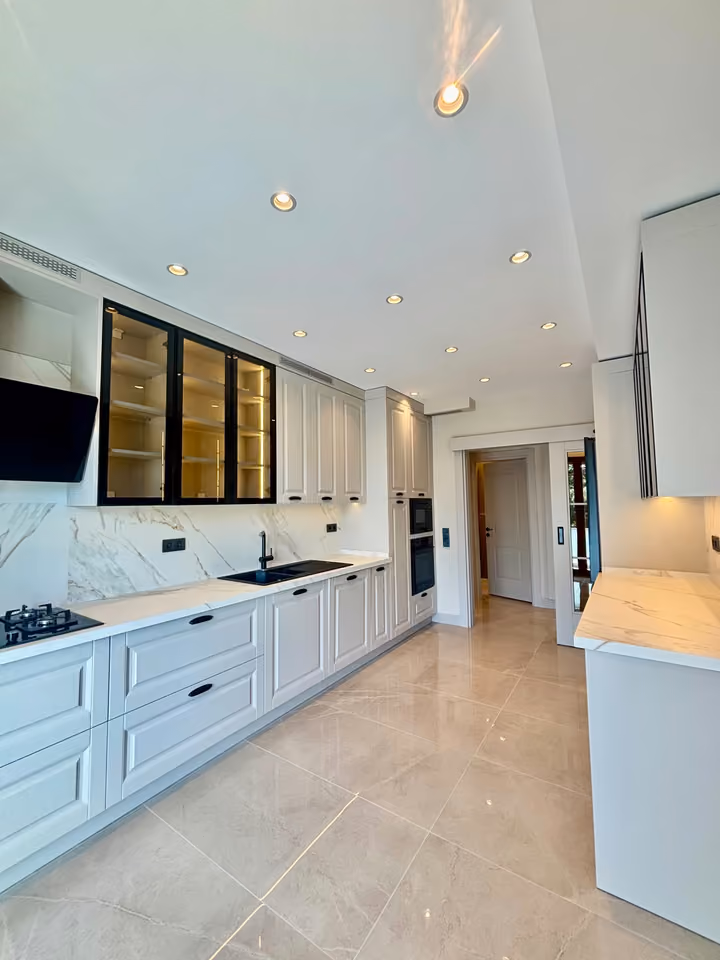 Kitchen with fitted cabinets, a cooktop, extractor hood and built-in ovens.