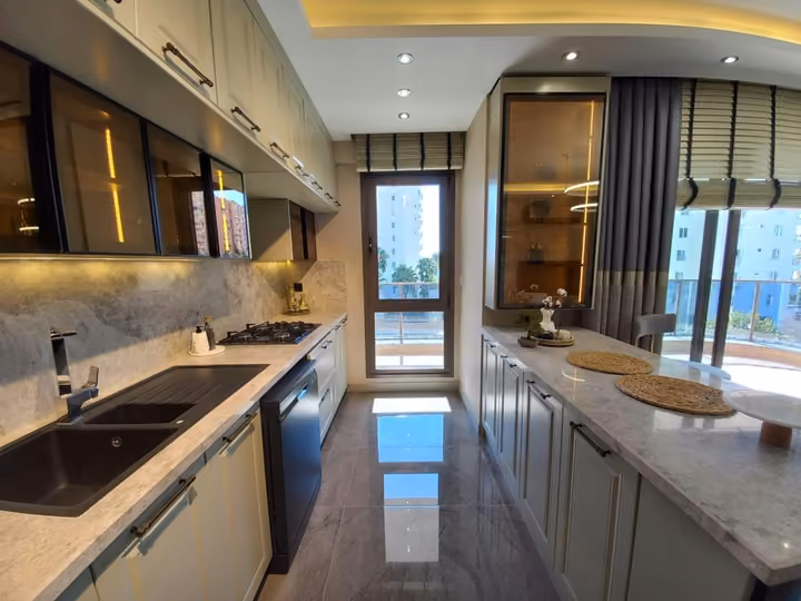 A furnished show apartment kitchen with an island and fitted cabinets.