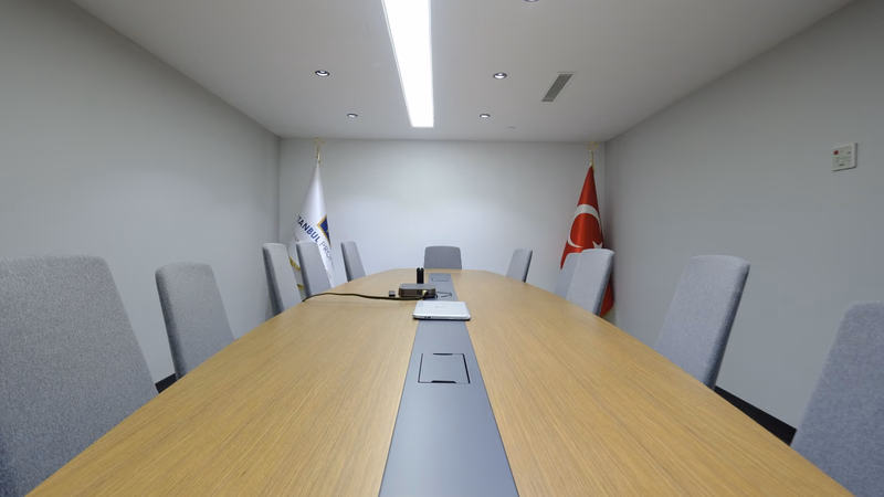 Переговорная комната Istanbul Property с длинным столом и флагами компании и Турции