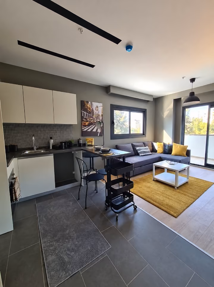 Photograph of an open kitchen beside a furnished sitting area.