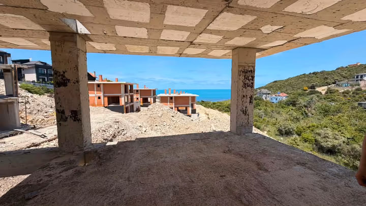 A wide view from an unfinished room toward construction and the sea. Undated photograph supplied in the construction source folder; it does not establish the current completion status.