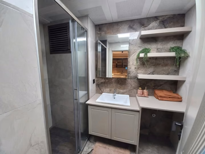 A show apartment bathroom vanity with illuminated mirror and open shelves.
