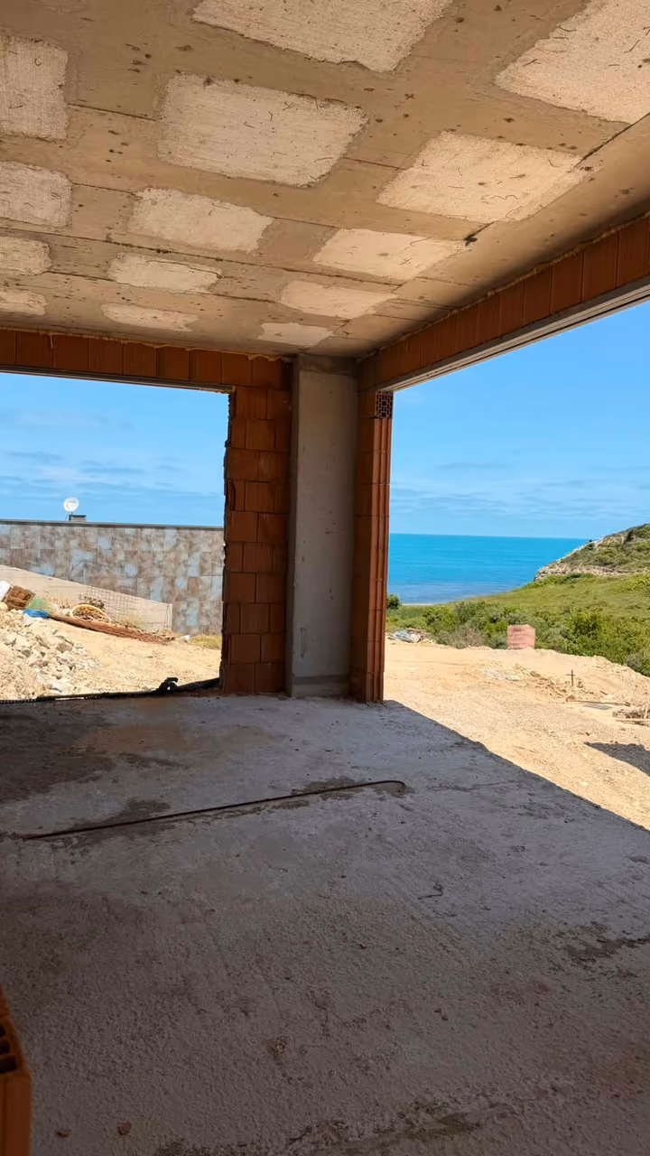 An unfinished corner room with broad openings toward the surrounding landscape. Undated photograph supplied in the construction source folder; it does not establish the current completion status.