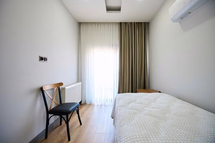 Bedroom with a double bed, desk and full-height curtains beside the window.