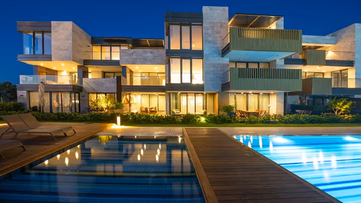 Illuminated apartments and pool at dusk in Boyalik, Cesme.