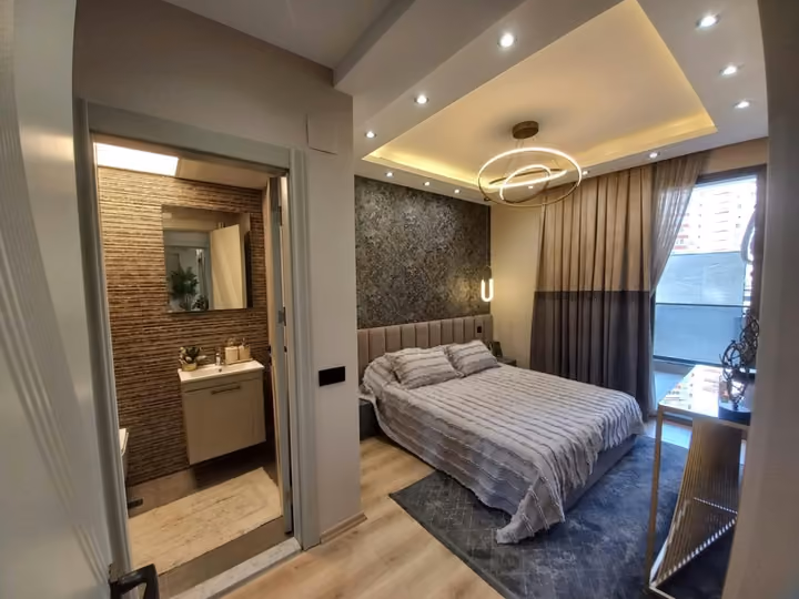 A furnished double bedroom with bedside storage and a balcony doorway.